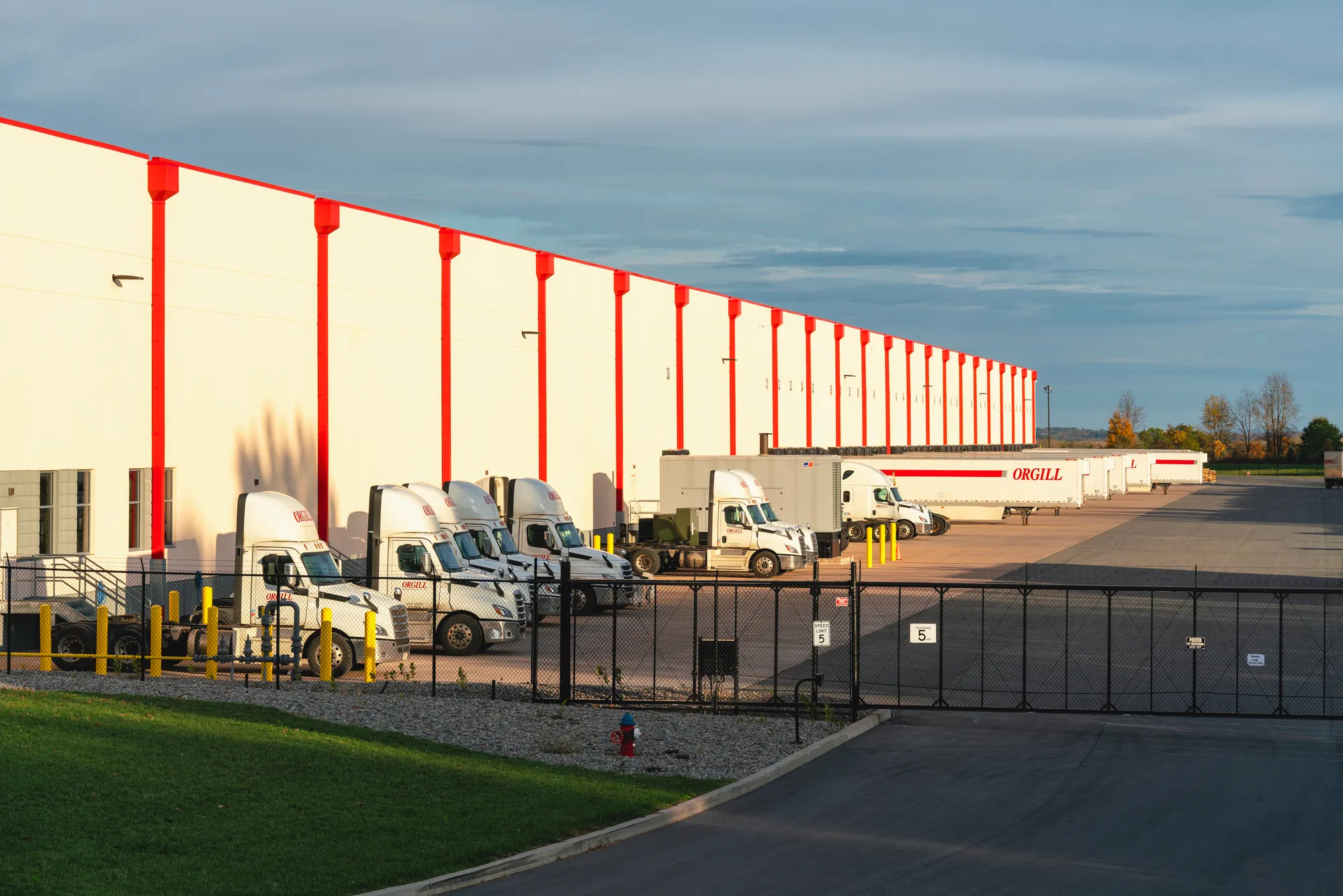 Exterior view of a premium Class A industrial warehouse building with a long row of semi-trucks parked at active concrete cross-dock loading bays in Dallas, TX