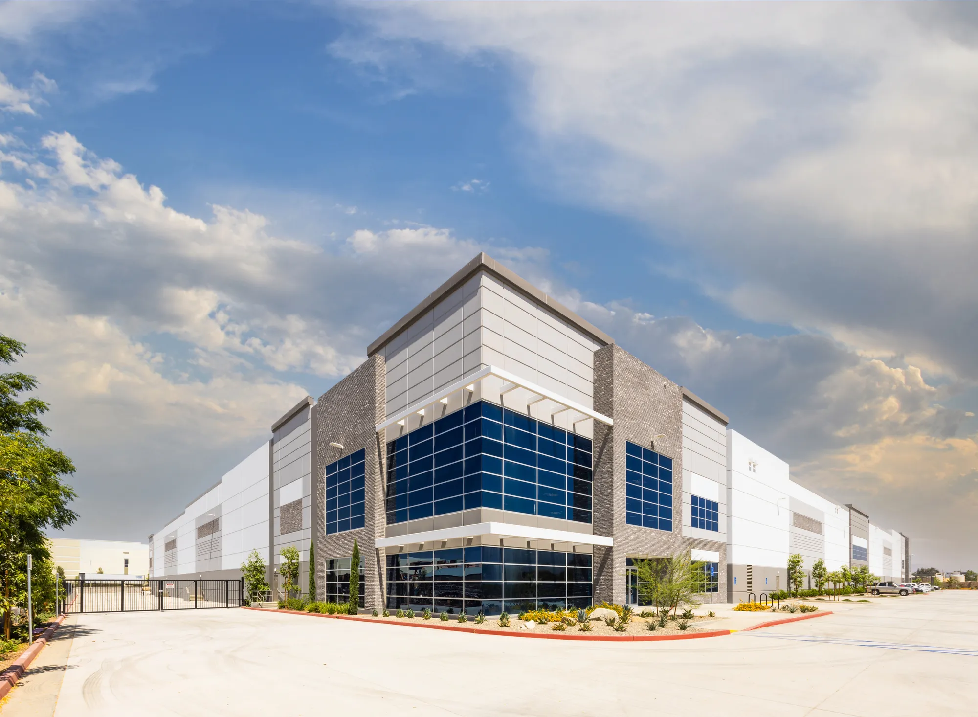 Angled exterior view of an ultra-modern Class A corporate flex industrial facility with a prominent blue glass curtain wall and stone panel accents in Durham, NC